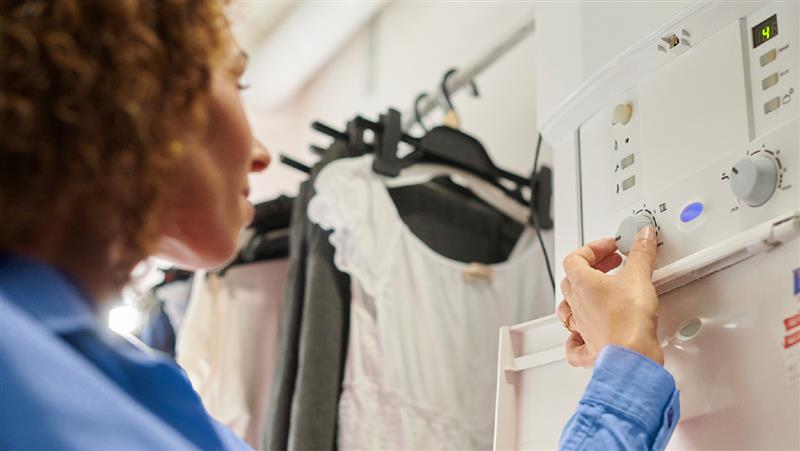 A woman in a blue shirt adjusts the temperature on her boiler