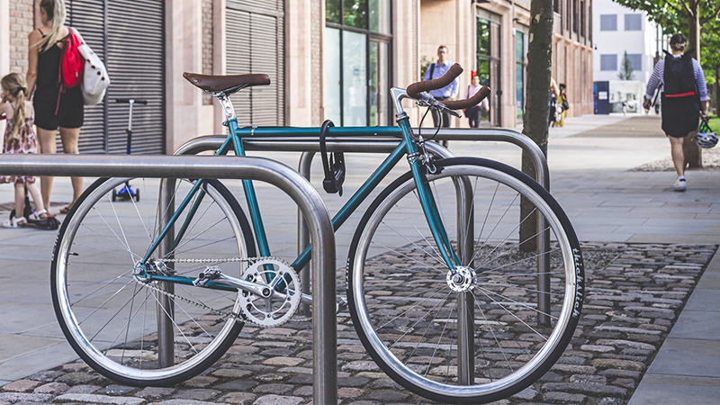A blue bike is secured to a bike rack.