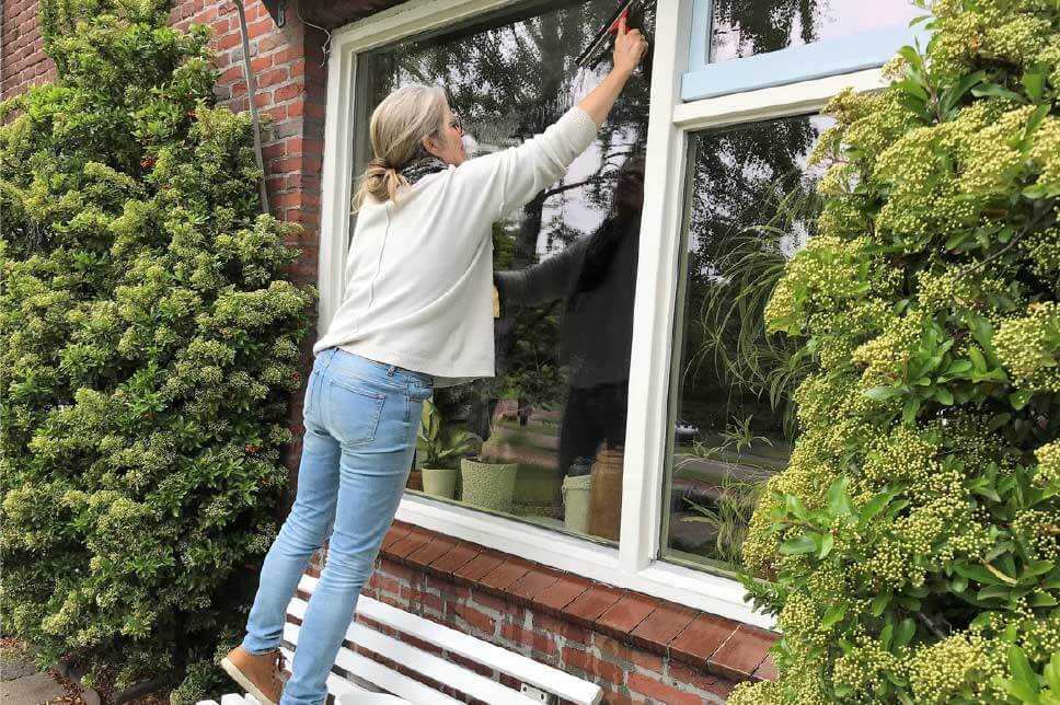 Woman cleaning her garden windows to get her house ready for summer