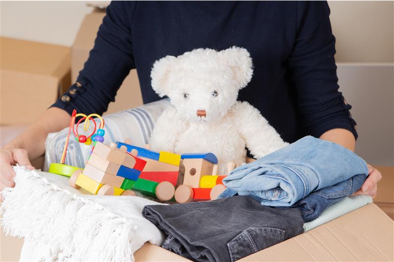 An adult carries a box full of childhood toys and clothing