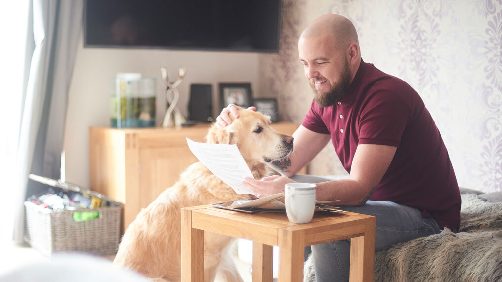 A man looks over some insurance documents beside his dog.